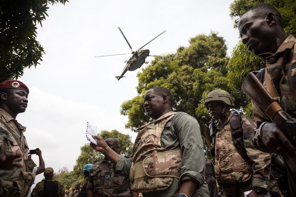 Le Premier ministre de la République centrafricaine Firmin Ngrebada salue ses troupes, alors qu’un hélicoptère de soutien russe survole la route entre Boali et Bangui, le 10 janvier 2021 (AFP)