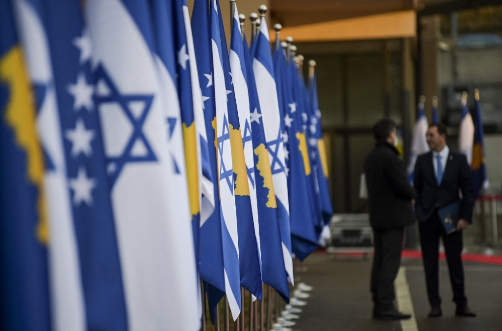 Kosovo's government officials stand in front of Kosovo's and Israel's flags displayed during a ceremony at the headquarters of the Foreign Ministry in Pristina on February 1, 2021 (AFP)