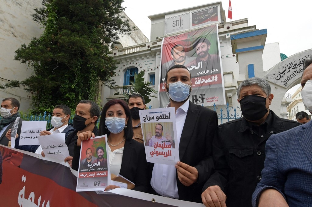 Des membres de l’Union des journalistes tunisiens posent avec des affiches en soutien aux journalistes marocains emprisonnés Omar Radi et Souleimane Raissouni, à ​​l’occasion de la Journée mondiale de la liberté de la presse à Tunis, le 3 mai 2021 (AFP/Fethi Belaïd)