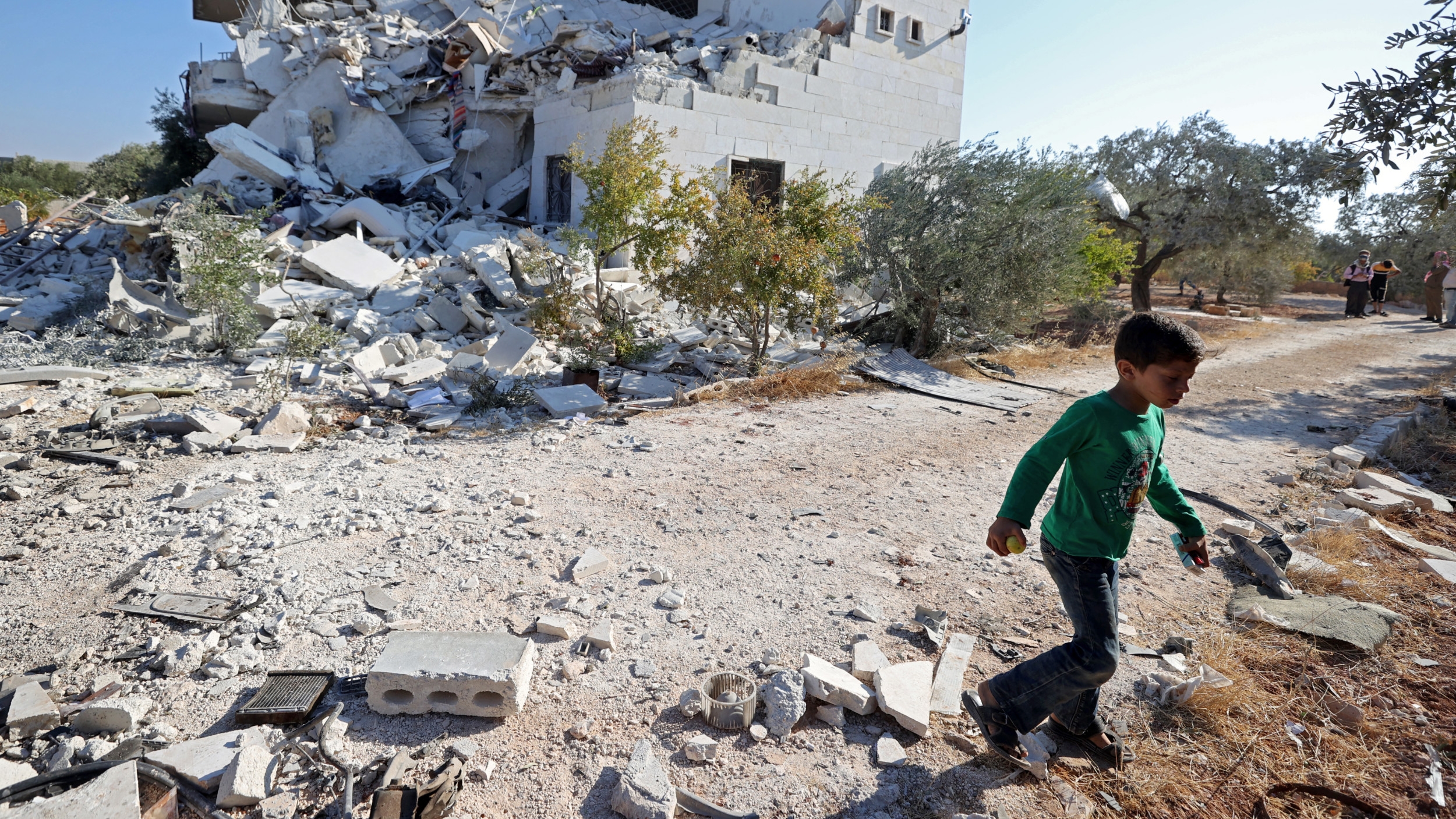 A Syrian child walks past destruction caused by Syrian government shelling in Idlib on 8 September 2021 (AFP)
