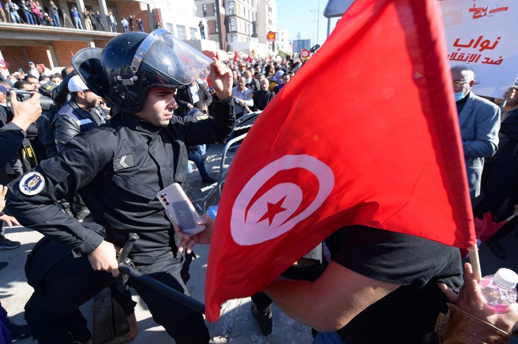Des manifestants tunisiens retirent des barrières métalliques lors d’affrontements avec les forces de sécurité, pendant une manifestation devant le Parlement à Tunis, le 14 novembre 2021 (AFP)