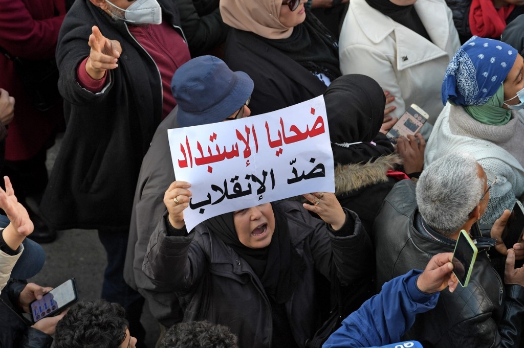 Une femme brandit une pancarte avec le slogan « Les victimes du despotisme contre le coup d’État », lors d’une manifestation à Tunis, le 17 décembre 2021 (AFP/Fethi Belaid)