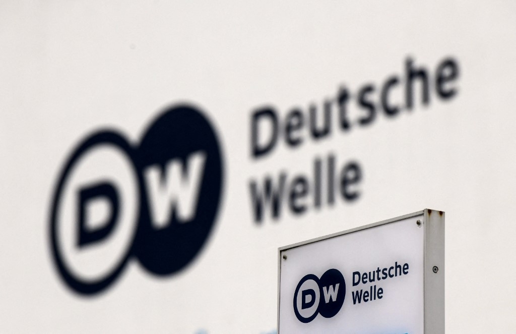 A picture shows a the logo of German international broadcaster Deutsche Welle (DW) on a board and on a wall at their head office in Bonn, Germany, on 8 February 2022 (AFP)