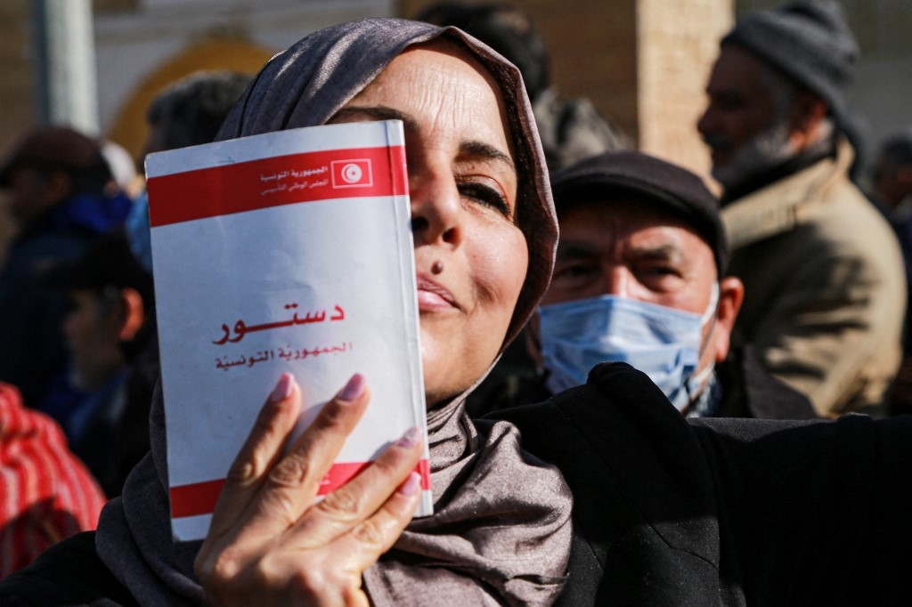 Une Tunisienne montre une copie de la Constitution, pendant une manifestation à l’appel du parti islamoconservateur Ennahdha, à Tunis, le 13 février 2022 (AFP/Anis Mili)