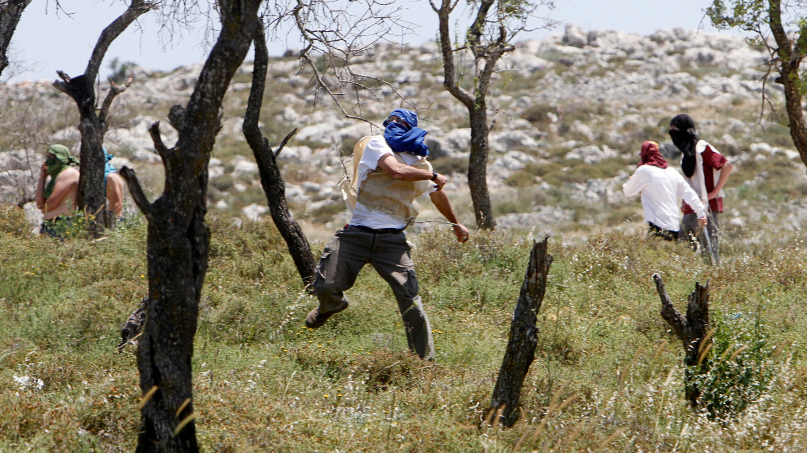 A masked Israeli settler throws stones towards Palestinians during clashes in the West bank village of Urif, near Nablus 30 April 2013 (Reuters)