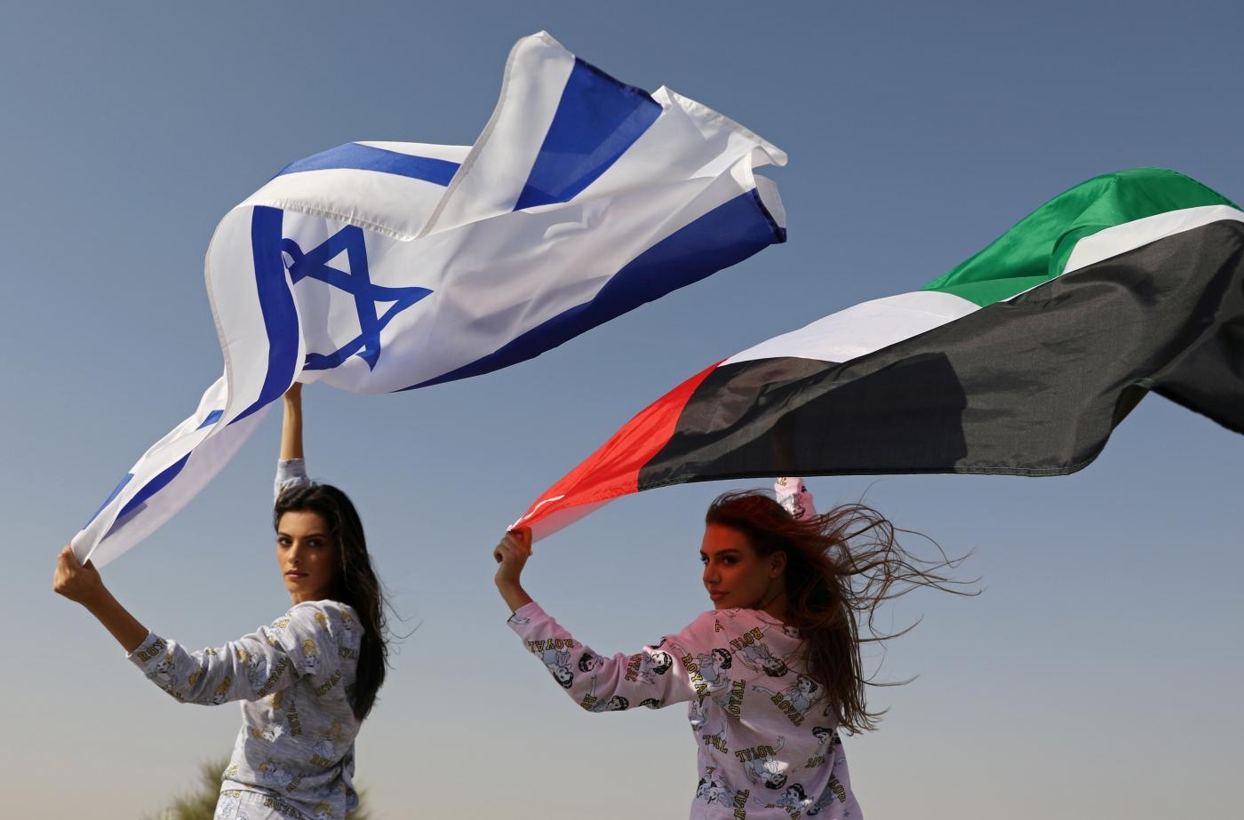 Des mannequins, l’une Israélienne et l’autre vivant à Dubaï, brandissent des drapeaux israélien et émirati pendant une séance photo dans le désert (Reuters)