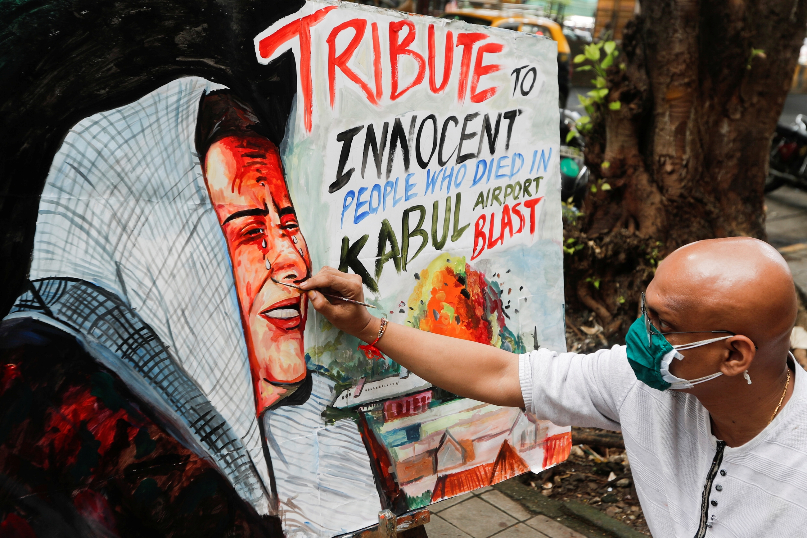 An artist paints a tribute to victims of the bomb blasts at the Hamid Karzai International airport in Kabul, outside an art school in Mumbai