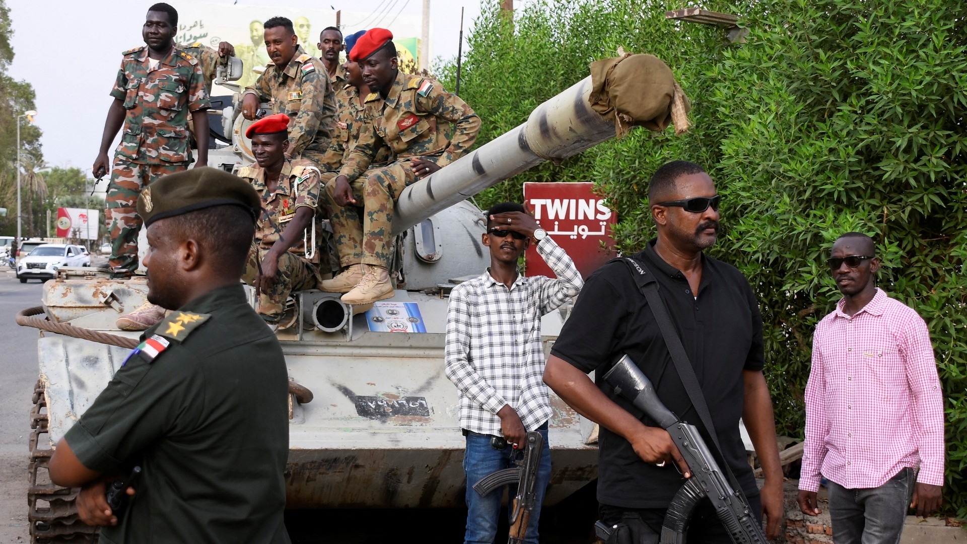 Members of military armed guard and members in plainclothes are seen around a tank after the arrival of Sudan's General Abdel Fattah al-Burhan in the military airport of Port Sudan on 27 August (Reuters)