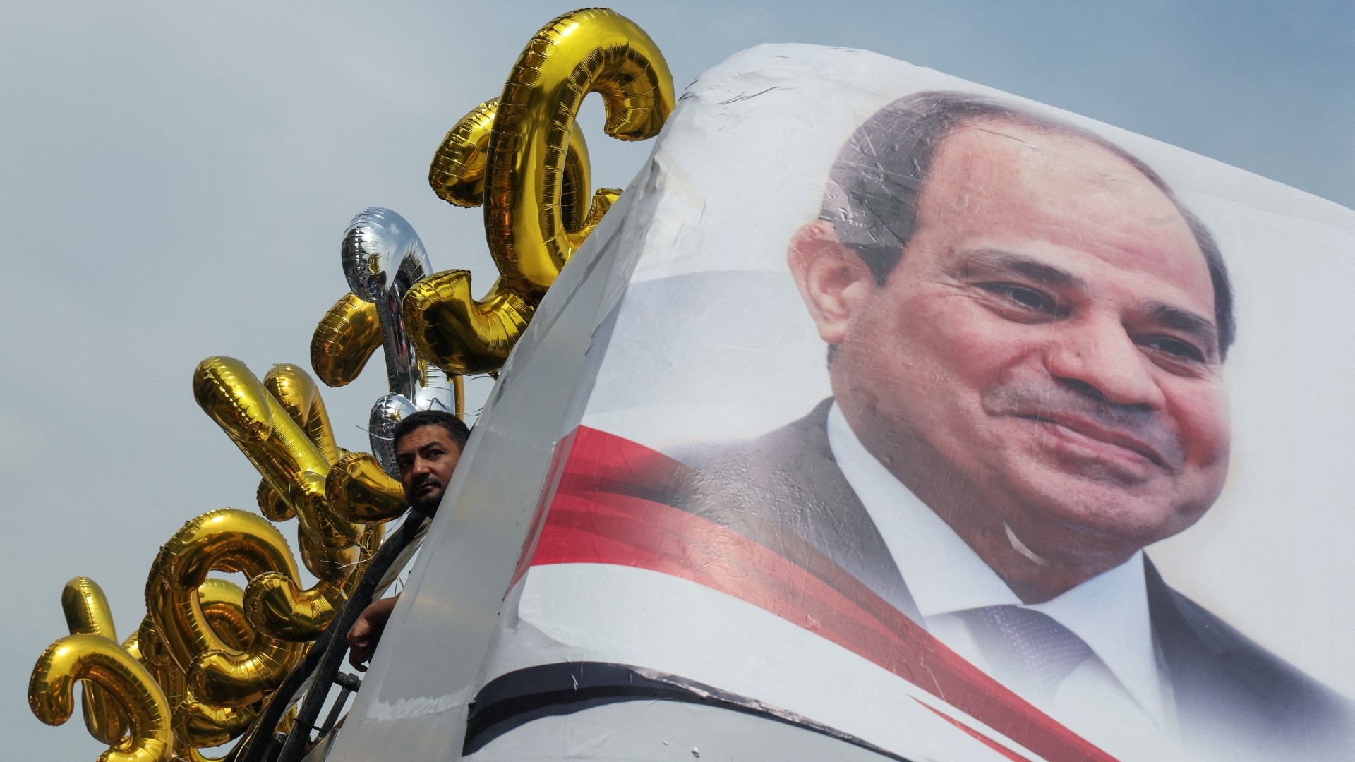 Un partisan d’Abel Fatah al-Sissi près d’une bannière représentant le président égyptien lors des préparatifs d’un rassemblement pour soutenir sa candidature à Gizeh, le 2 octobre (Reuters)