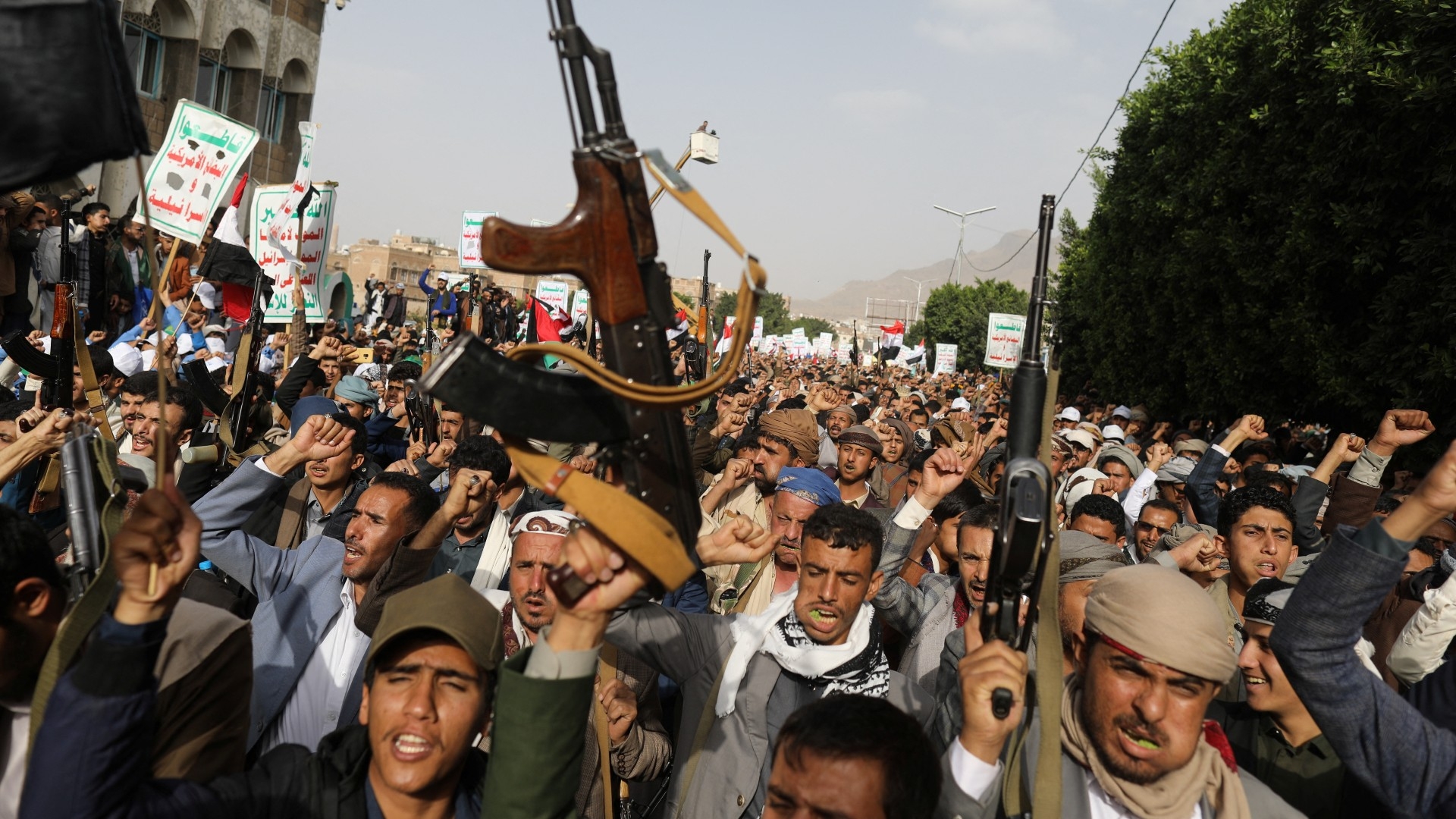 Armed men hold up their weapons as Houthi supporters rally to show support to Palestinian factions, in Sanaa, 7 October (Reuters)