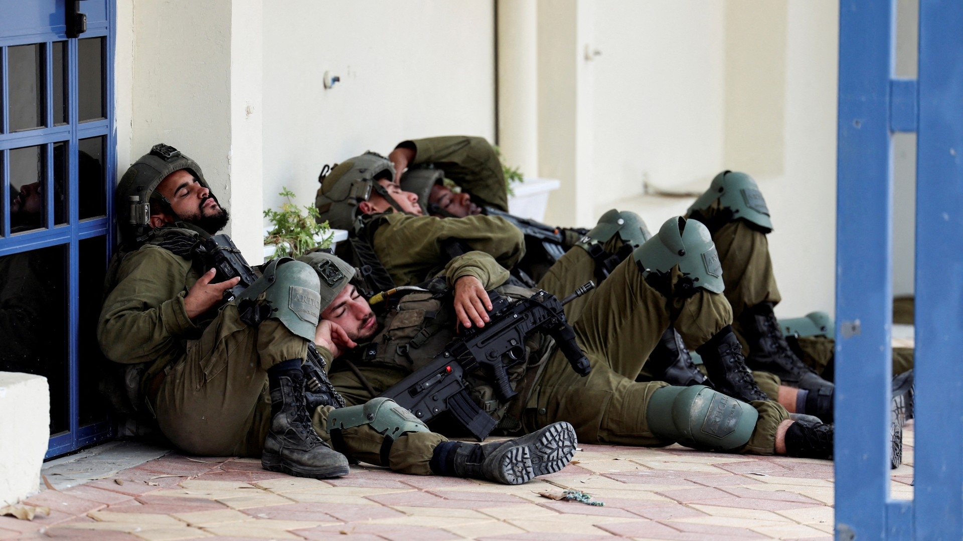 Israeli soldiers rest near a building the day after a mass attack by Hamas gunmen from the Gaza Strip, in Sderot, southern Israel 8 October (Reuters)