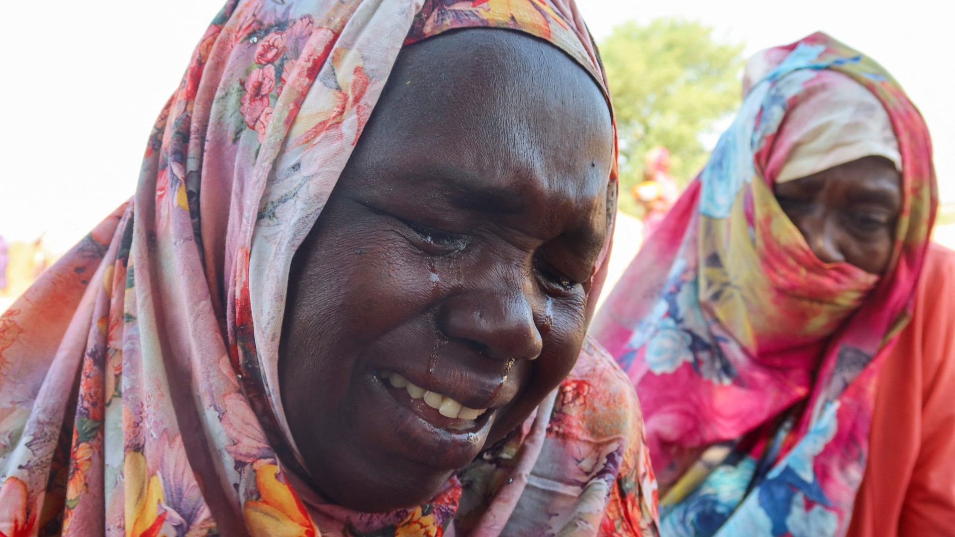 Women from the city of el-Geneina cry after receiving the news about the death of their relatives as they waited for them in Chad on 7 November (Reuters)