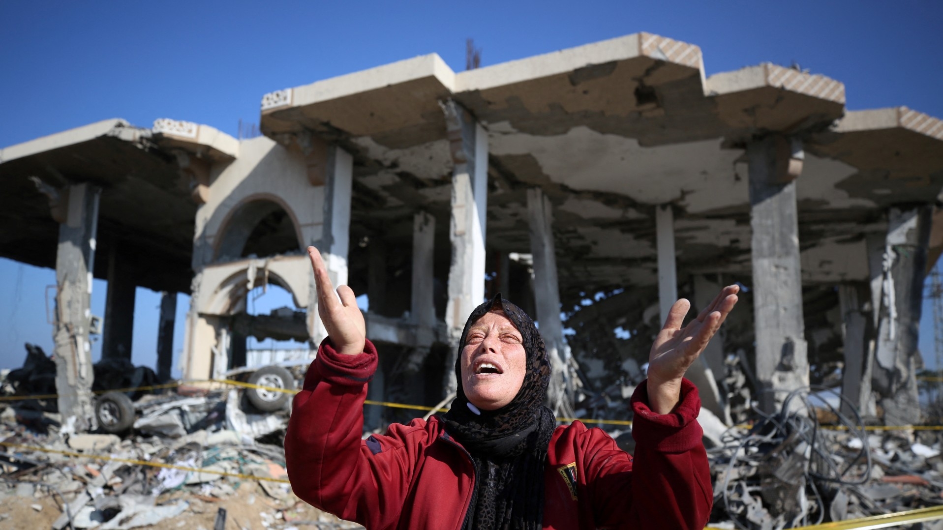 A Palestinian woman reacts in front of a destroyed building in the Al-Maghazi refugee camp in central Gaza Strip, on 16 January, 2024 (AFP)