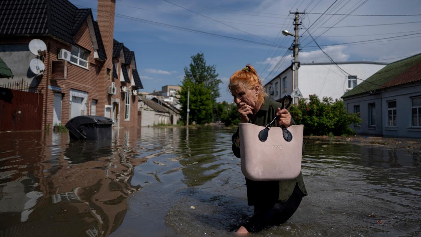 Une habitante se fraie un chemin dans les eaux après la rupture du barrage de Kakhovka à Kherson, en Ukraine, le 6 juin 2023 (AP)