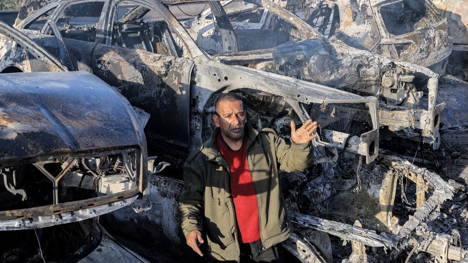 A man stands amid destroyed cars in the town of Huwwara near Nablus in the occupied West Bank on 27 February 2023 after they were torched overnight by Israeli settlers (AFP)