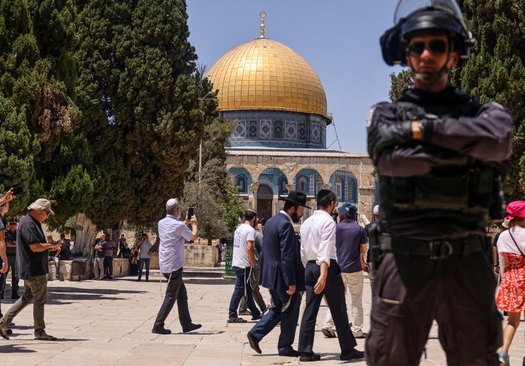  A member of Israeli security forces stands guard, as a group of Jewish settlers enter the al-Aqsa mosque compound in occupied East Jerusalem, 18 July 2021 (AFP)