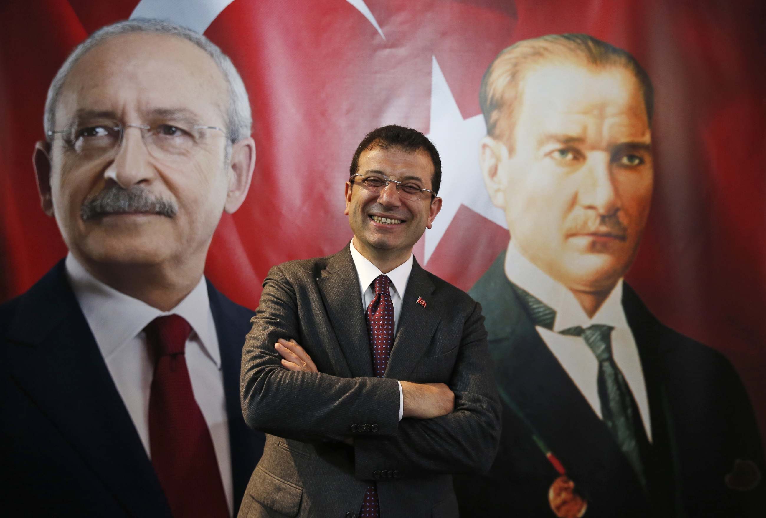 Backdropped by a poster of Kemal Kilicdaroglu, left, and Mustafa Kemal Ataturk, right, Ekrem Imamoglu poses for a photo in 2019 (AP)