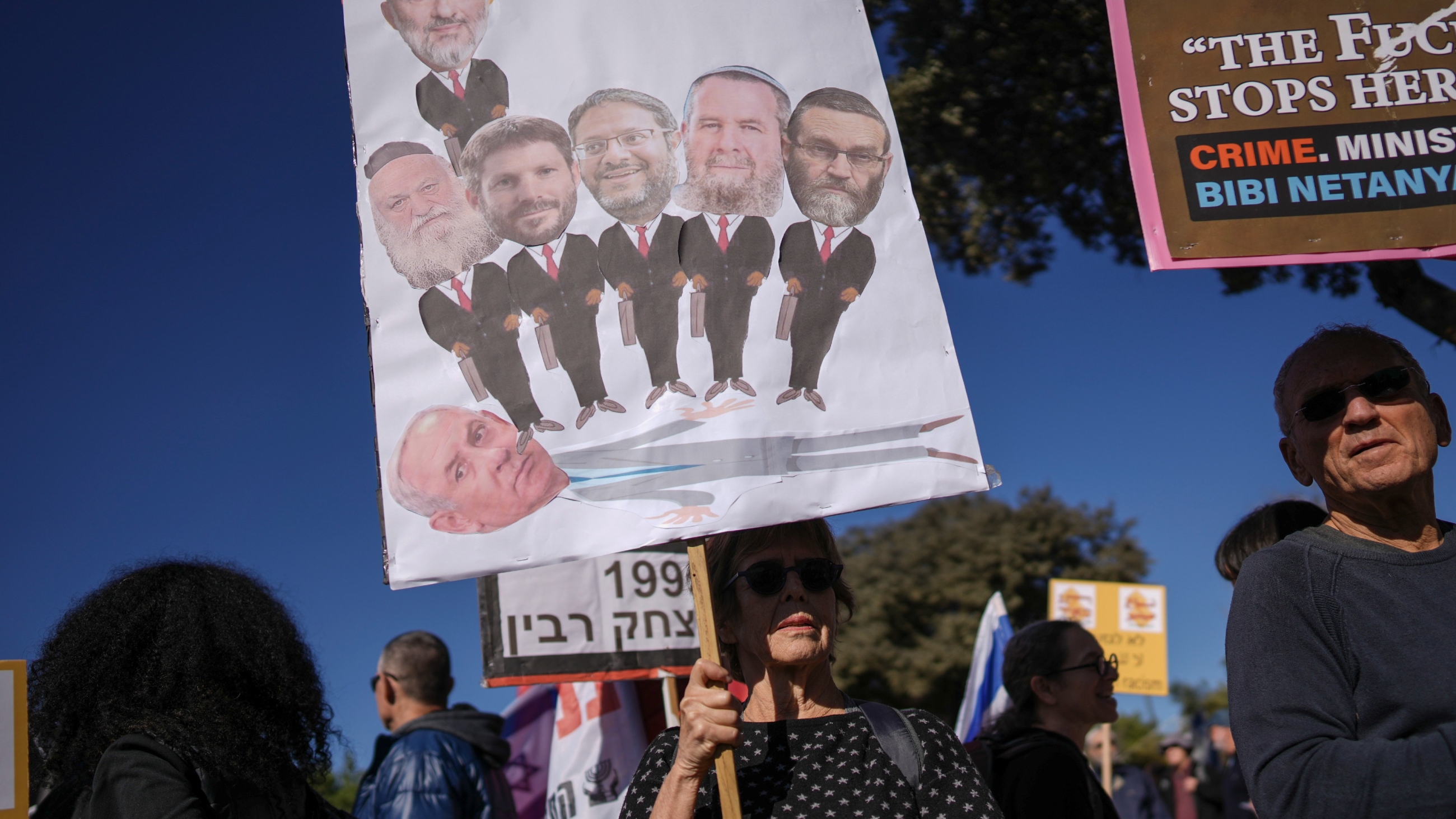 Protesters hold banners against Benjamin Netanyahu's new government in front of Israel's parliament in Jerusalem on 29 December 2022 (AP)