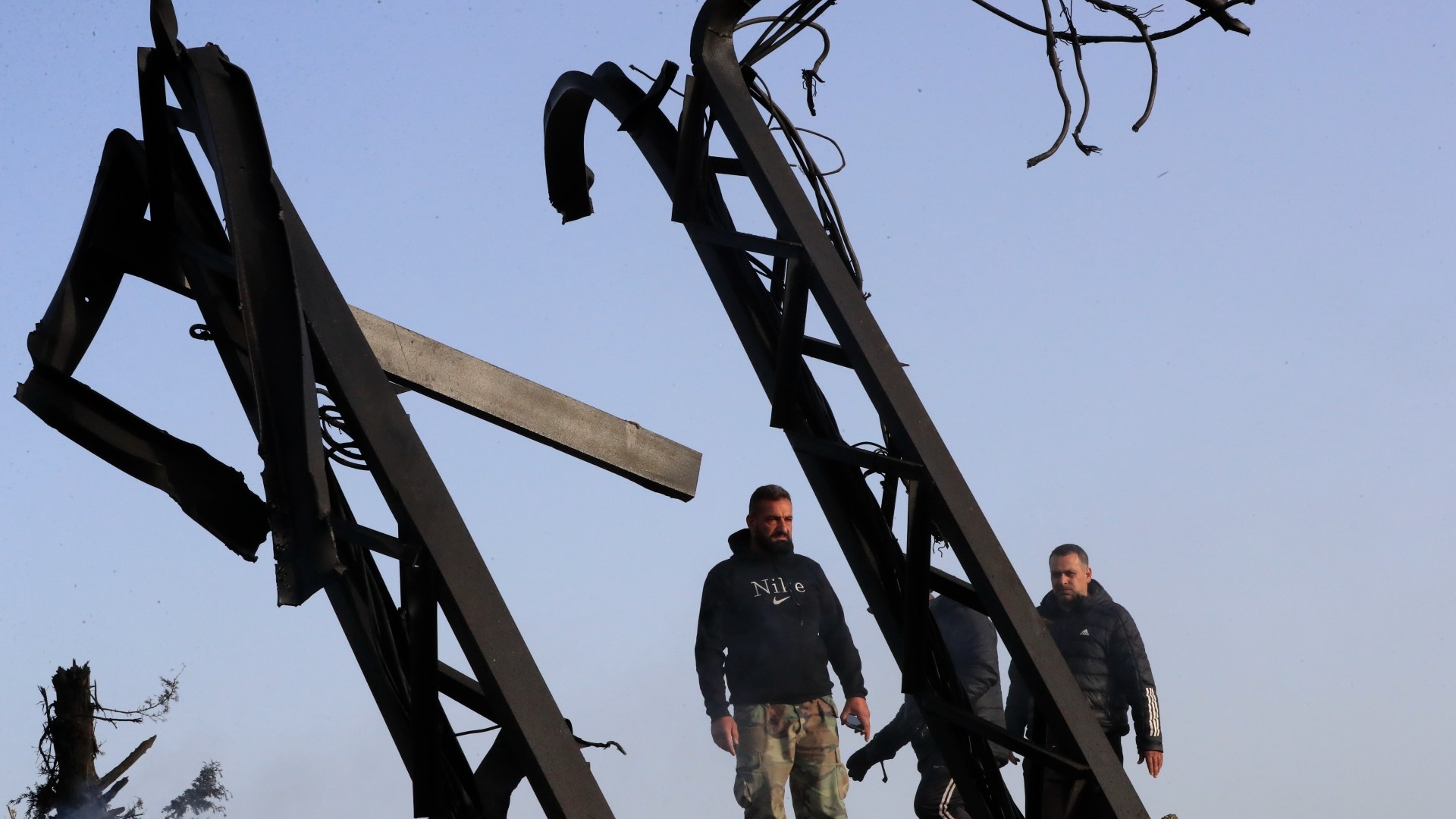 Lebanese check a power transformer poles that were destroyed by an Israeli air strike, in Maaliya village, south Lebanon, 7 April (AP)
