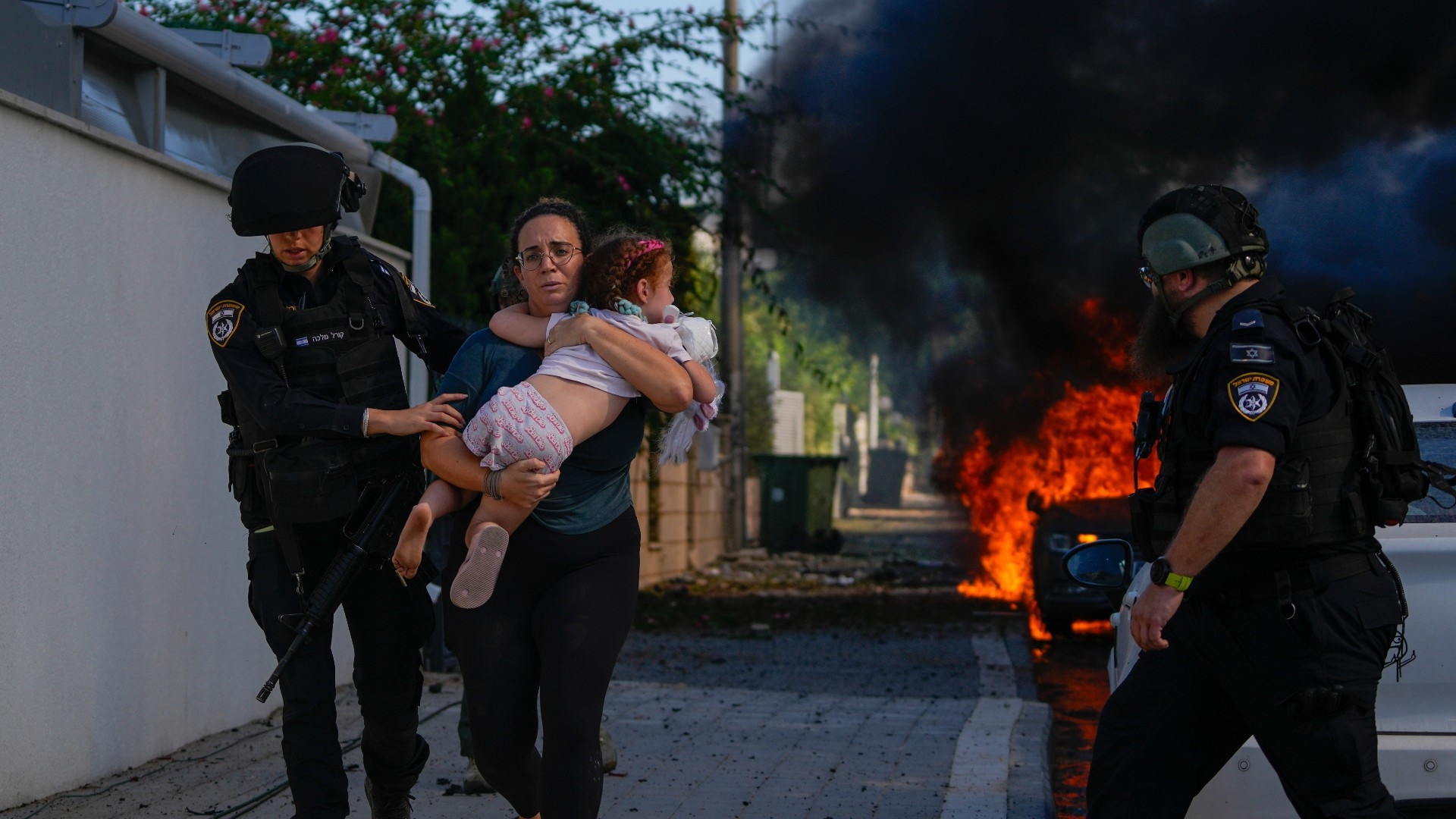 Police evacuate a woman and a child from a site hit by a rocket fired from the Gaza Strip, in Ashkelon (AP)