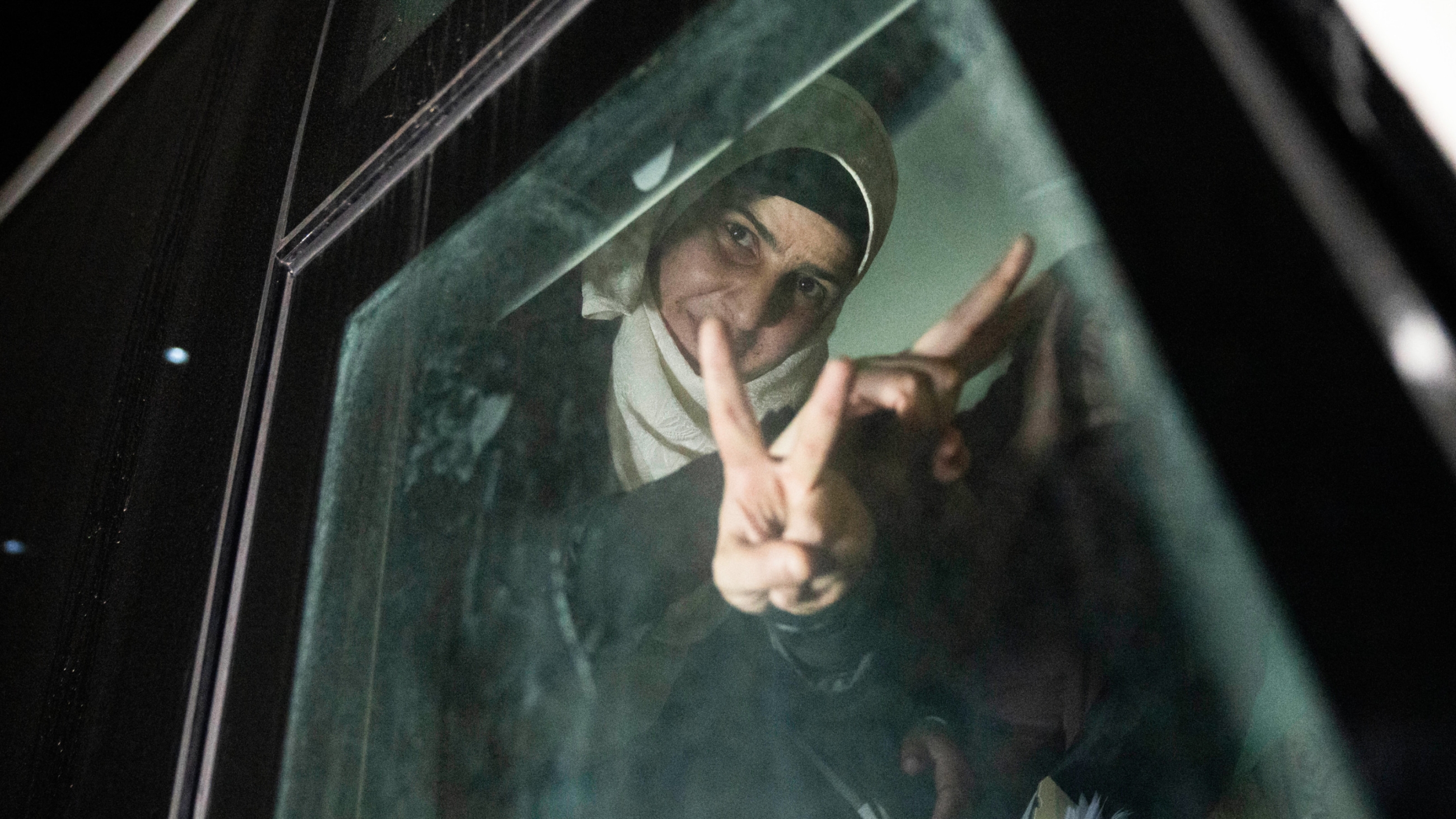 Palestinian women flash the "V" sign inside their transportation upon their arrival in the West Bank after being freed from Israeli jail on 24 November 2023 (AP)