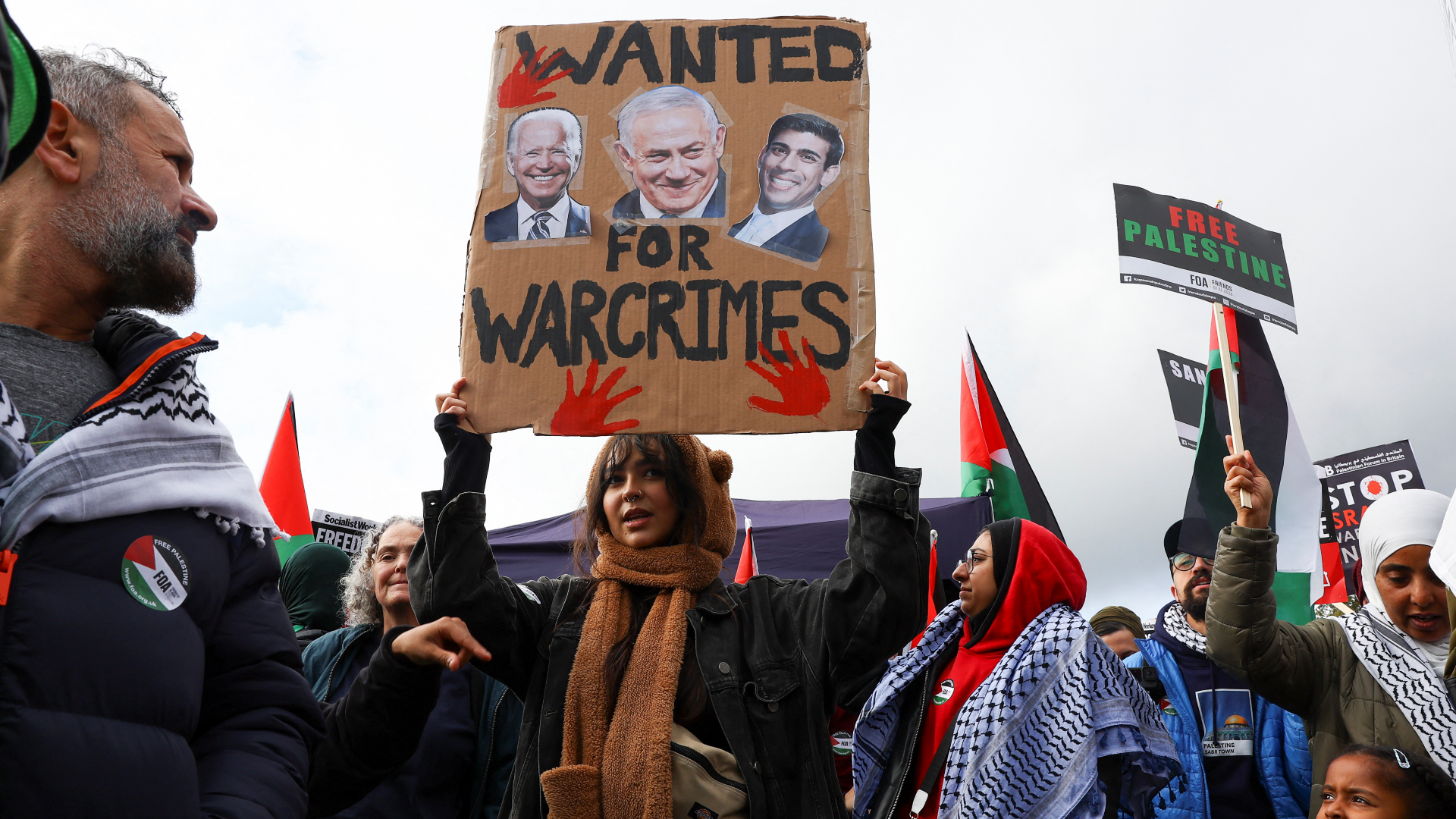 A demonstrator holds up a sign featuring images of US President Joe Biden, Israeli Prime Minister Benjamin Netanyahu, and British Prime Minister Rishi Sunak, at a protest in solidarity with Palestinians in Gaza, in London, Britain on 21 October 2023 (Reuters)