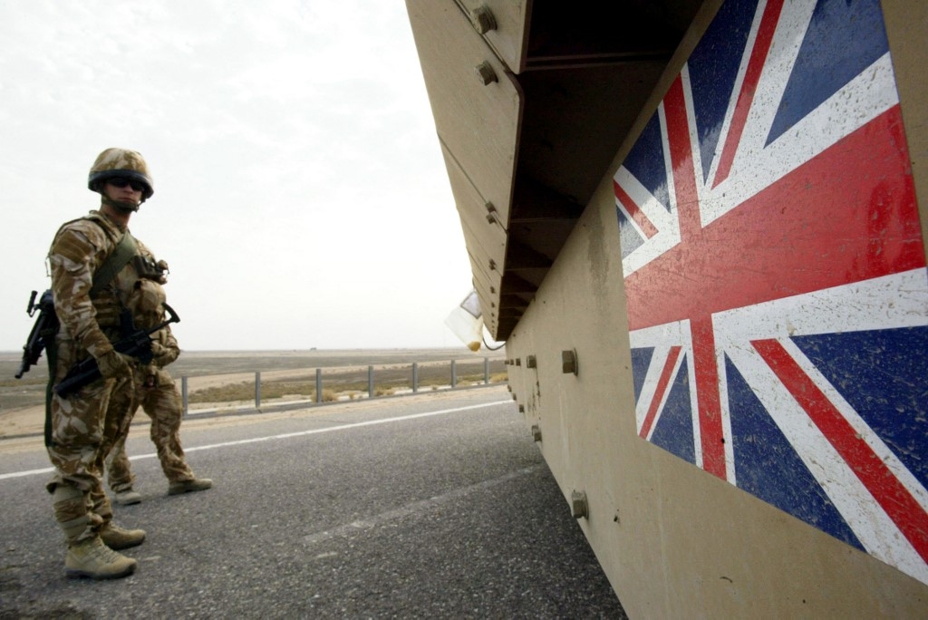 British soldiers keep watch as a tank passes ahead of the security transfer between British and Iraqi troops in Basra on 16 December 2007