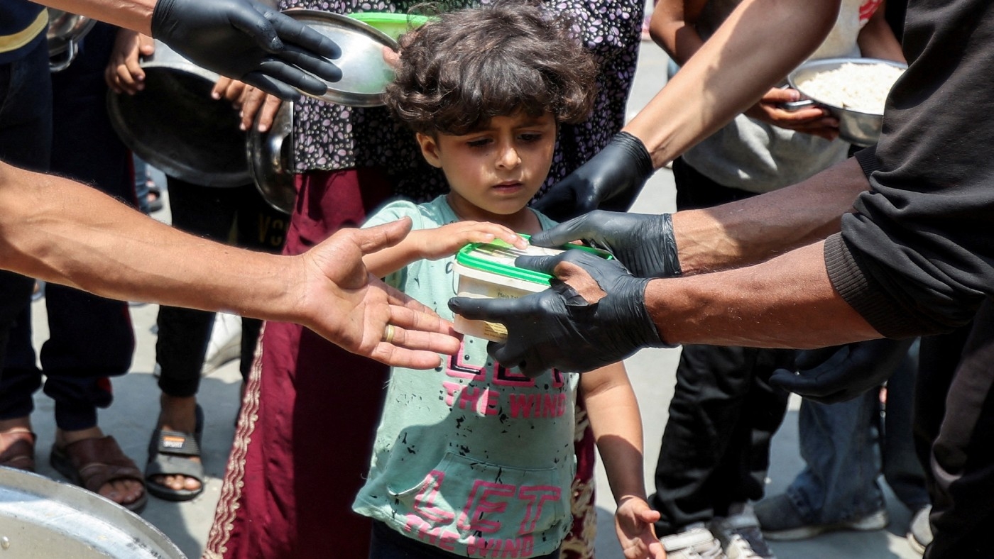 A Palestinian child receives food cooked by World Central Kitchen (WCK) in Deir al-Balah in the central Gaza Strip 1 May 2024 (Reuters)