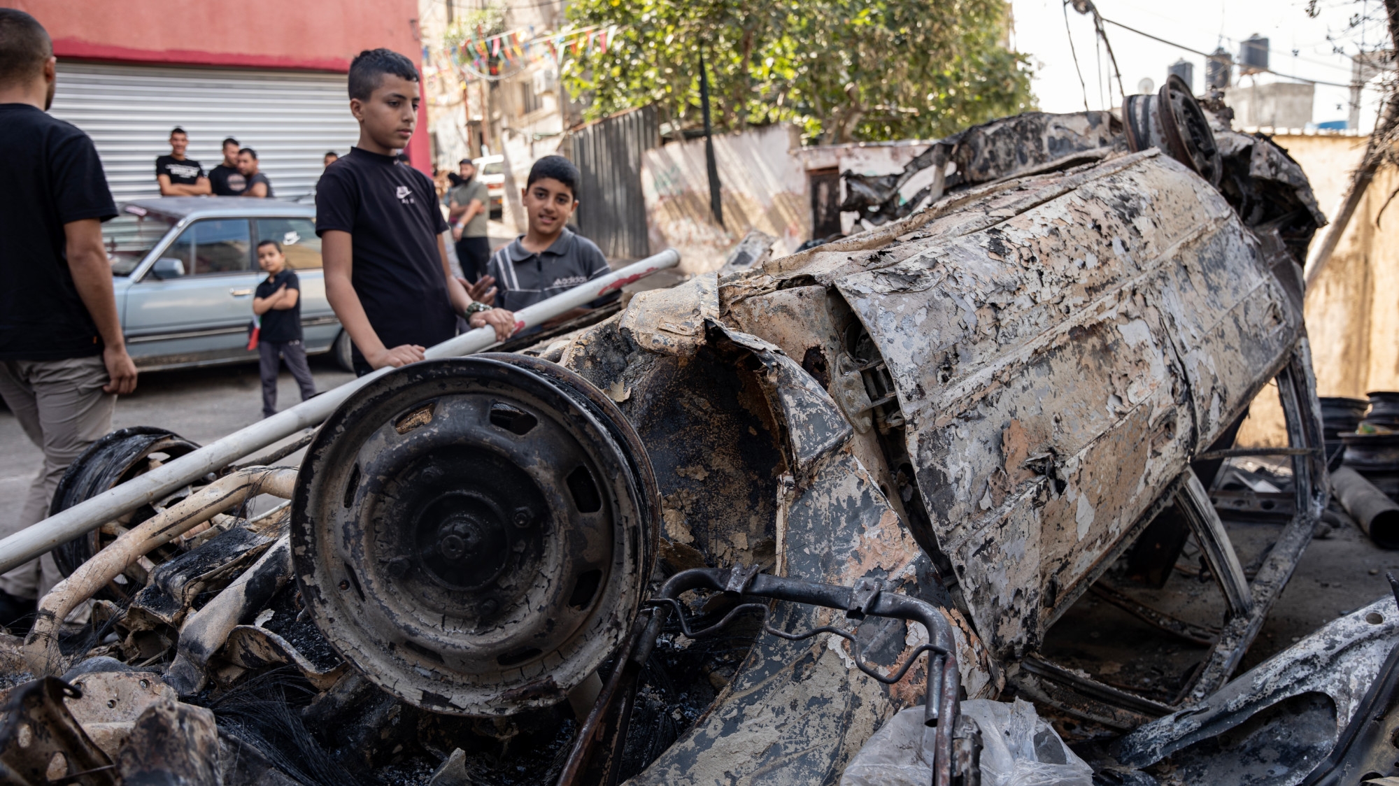 Palestinian children inspect a car damaged during a raid by Israeli troops at the Nour Shams refugee camp in the occupied West Bank on 20 October 2023 (MEE/Latifeh Abdellatif)