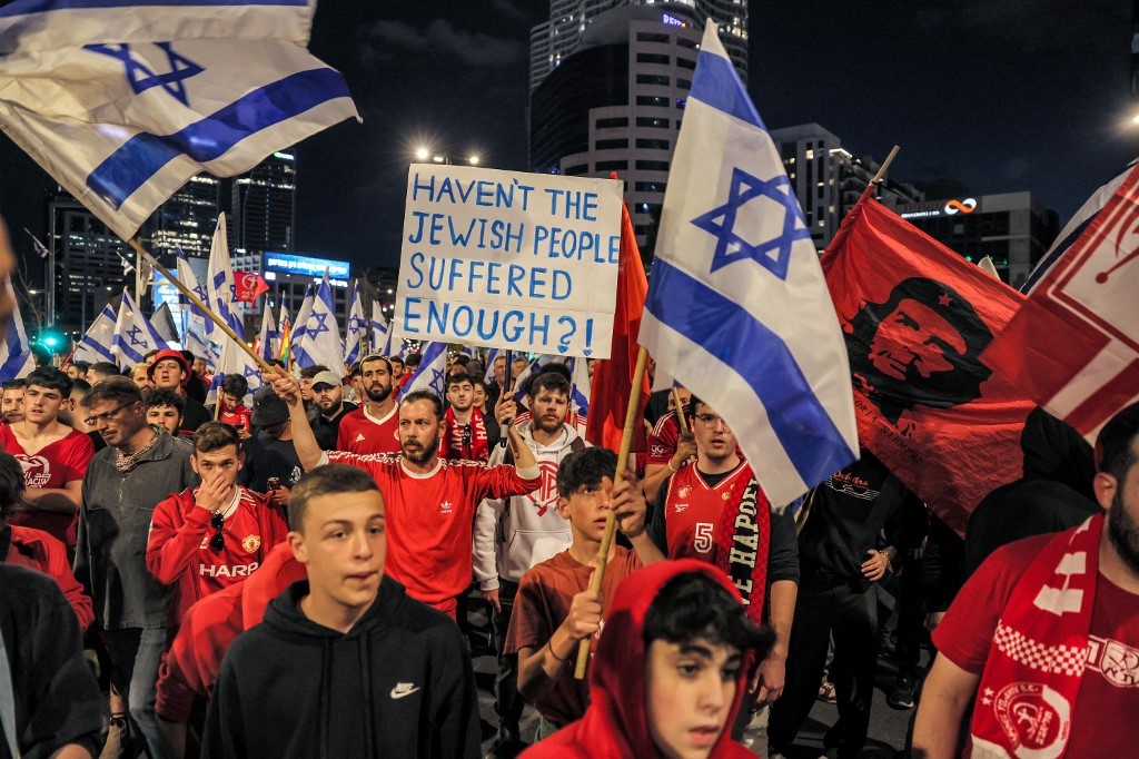 Demonstrators march with signs and Israeli flags during a rally against the government's judicial reform bill in Tel Aviv on 1 April 2023 (AFP)