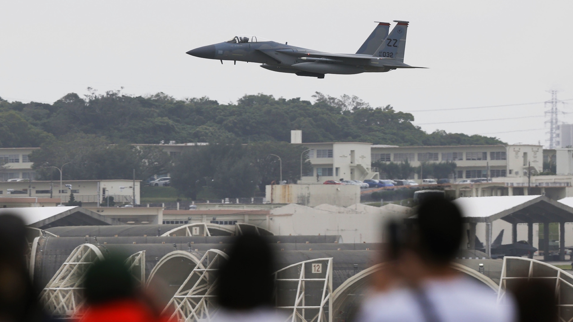 Observers look on as an F-15 Strike Eagle, the only fighter jet fitted with JDAM and GBU-39 munitions, flies at the US Air Force's Kadena base in Okinawa Prefecture, southern Japan, on 14 December 2022 (Kyodo via Reuters)