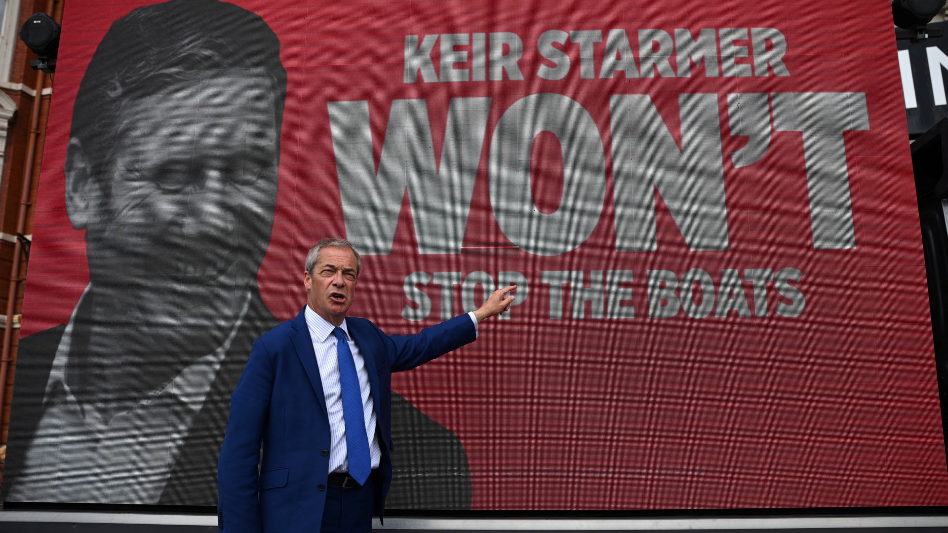 Leader of Reform UK Nigel Farage stands in front of a van reading "Keir Starmer won't stop the boats" in reference to migrant crossings across the Channel during a campaign event in Blackpool, northwestern England, on 20 June (Oli Scarff/AFP)