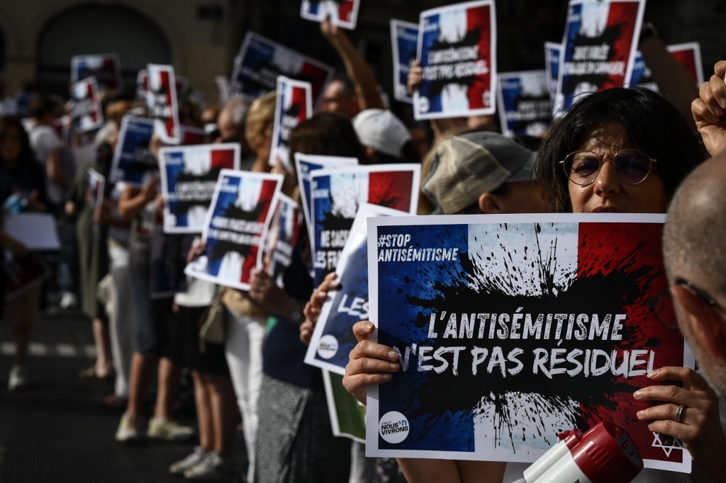 Protesters hold placards which read 'Anti-Semitism is not residual' as they gather to condemn the alleged anti-semetic gang rape of a 12 year-old girl, in Lyon, France, on 19 June 2024 (Jean-Philippe Ksiazek/AFP)