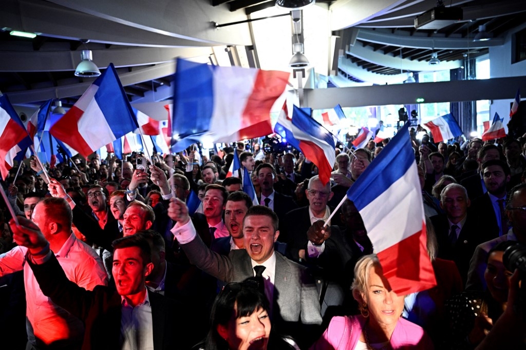 Far-right National Rally party members celebrate the announcement of the European Parliament election results at the Pavillon Chesnaie du Roy in Paris on 9 June (Julien de Rosa/AFP).