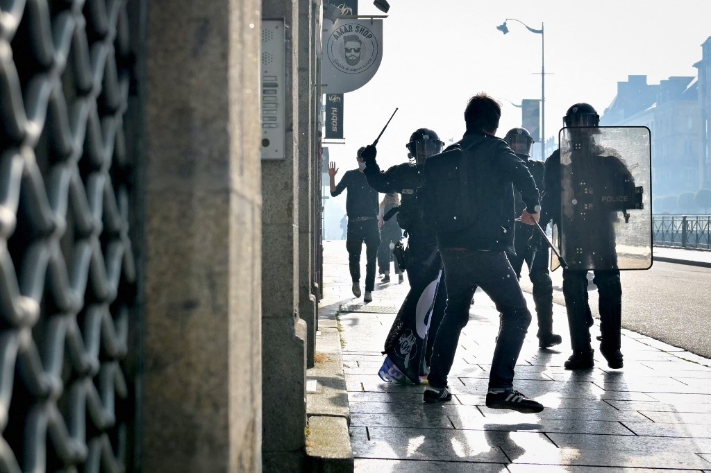 Riot police officers charge at a protester during a demonstration against the rise of far-right parties, in Rennes, northwestern France, on 20 June (Lou Benoist/AFP)