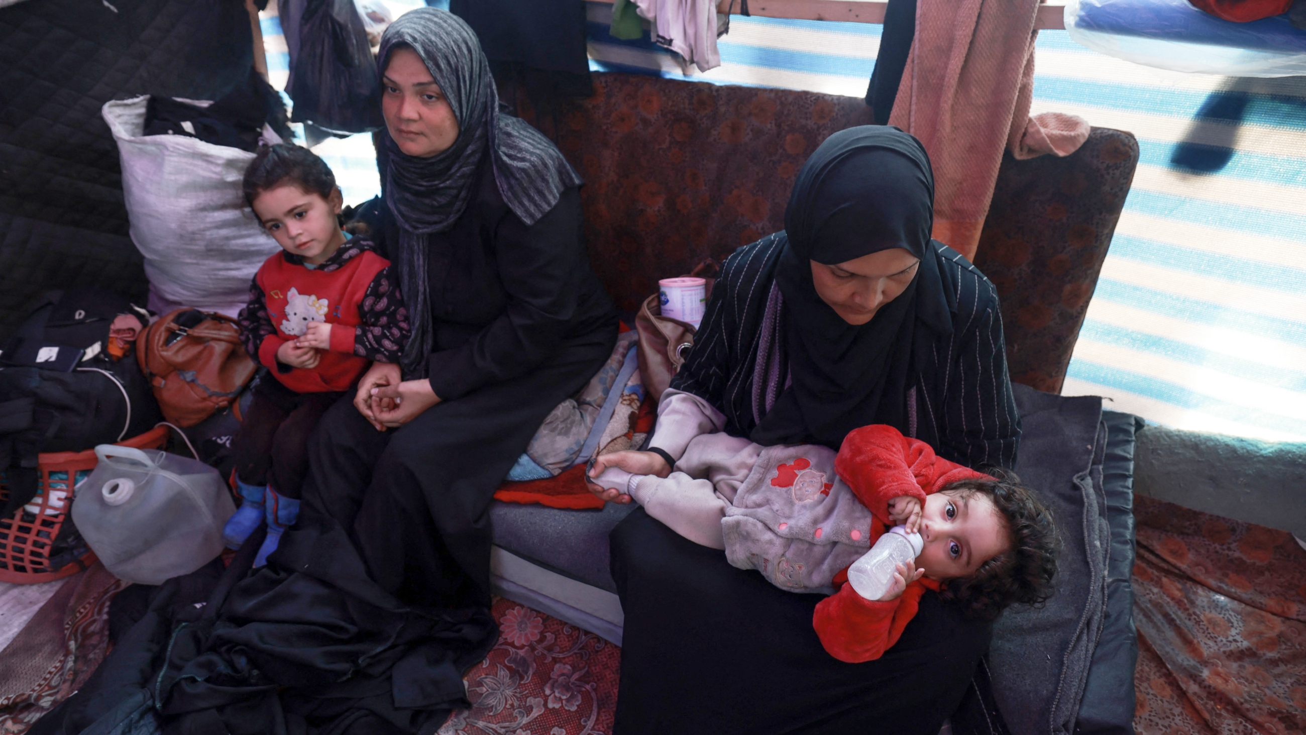 Displaced Palestinian women take care of their children inside a tent in Rafah in the southern Gaza Strip on 7 March 2024, on the eve of International Women's Day, amid Israel's ongoing bombardment (Mohammed Abed/AFP)