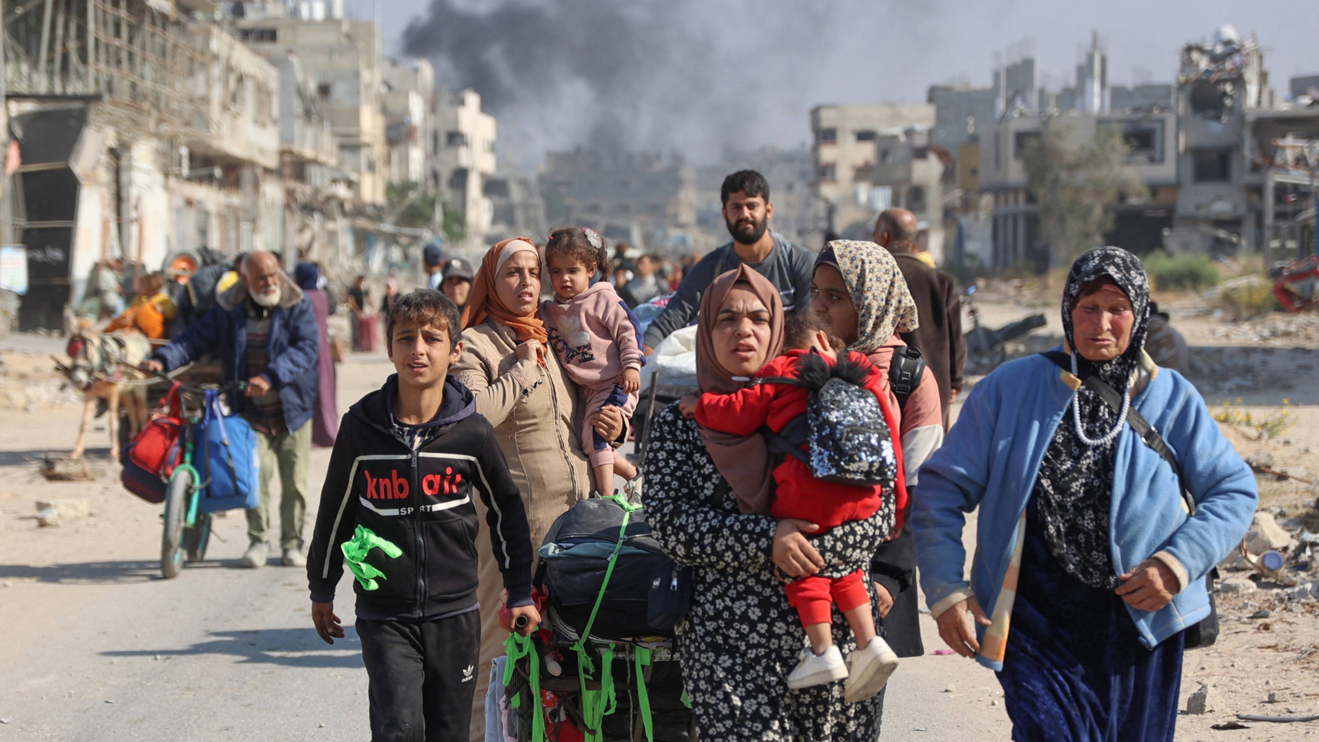 Palestinians displaced from shelters in Beit Hanoun cross the main Salah al-Din road into Jabalia in the northern Gaza Strip on 12 November 2024 (AFP)