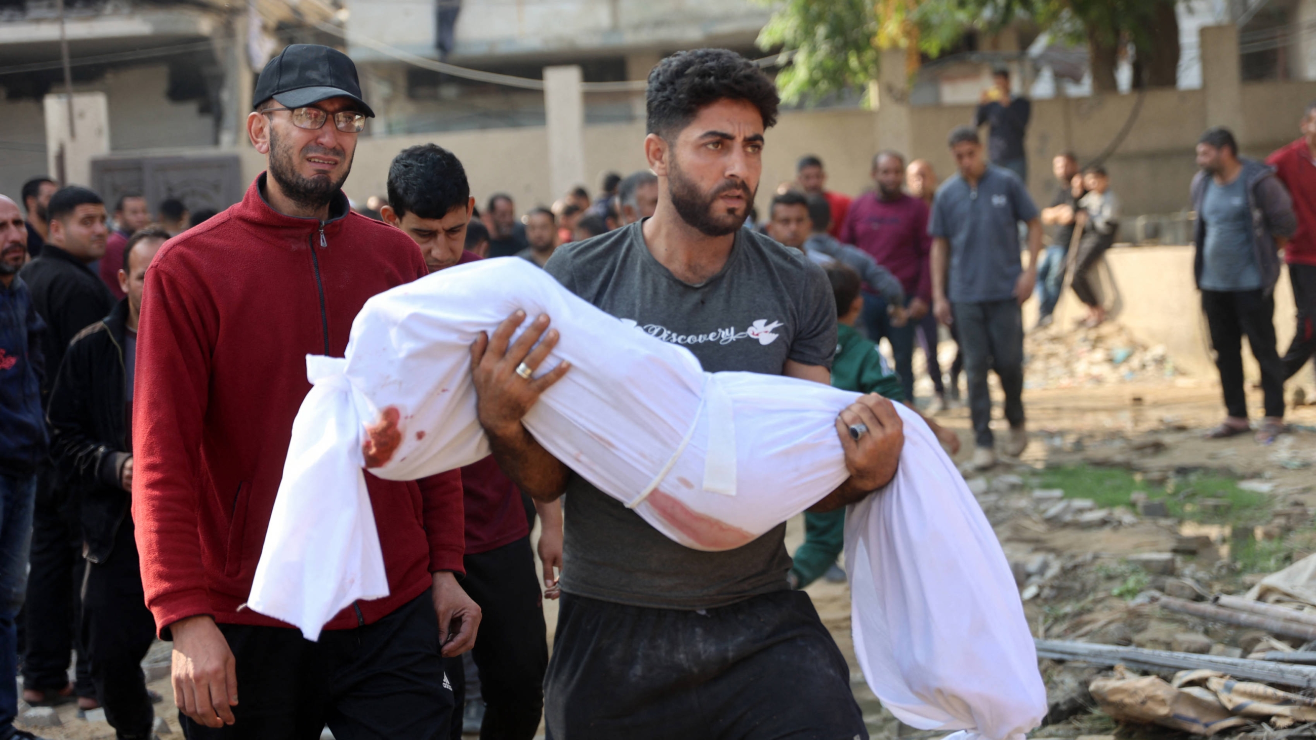 A Palestinian man carries the body of a victim killed in Israeli strikes toward a cemetery in Jabalia in the northern Gaza Strip on 10 November 2024 (AFP)