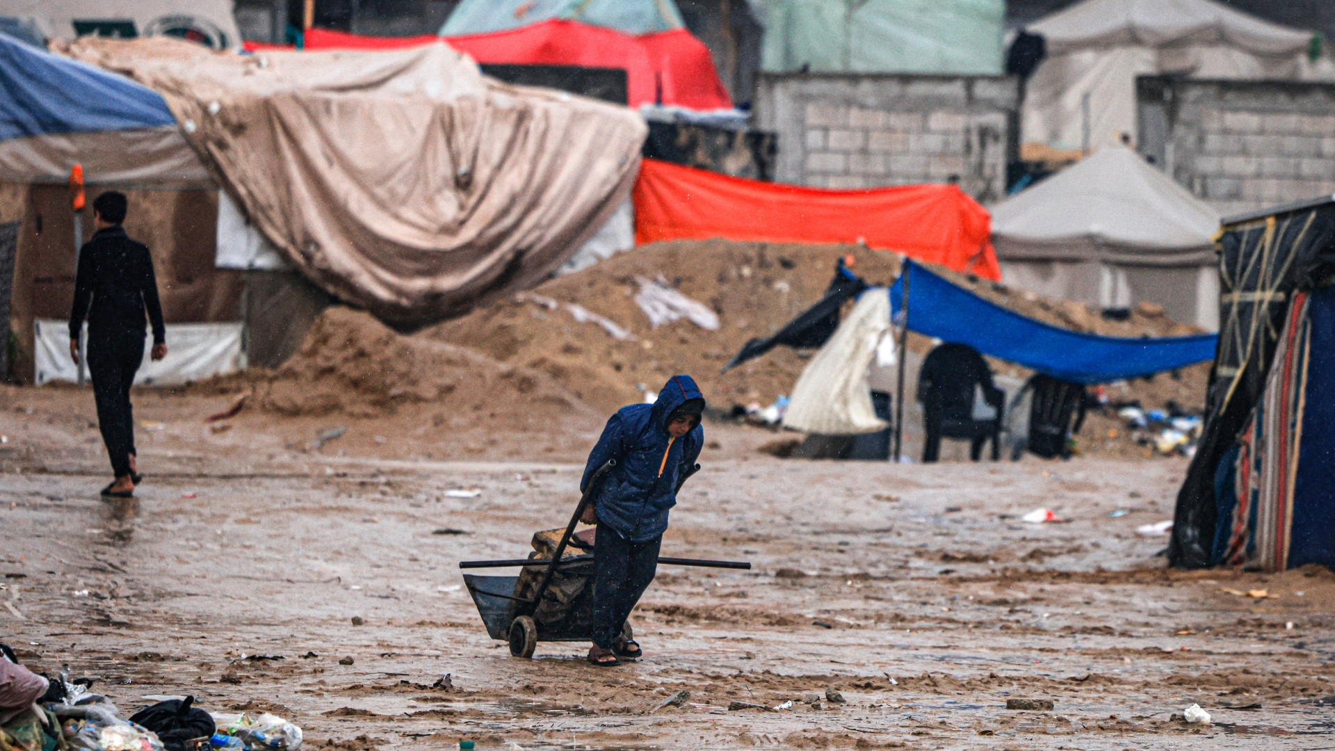 A Palestinian drags bricks at a camp for displaced people in Rafah, in the southern Gaza Strip where most civilians have taken refuge, on 13 December 2023 (AFP)