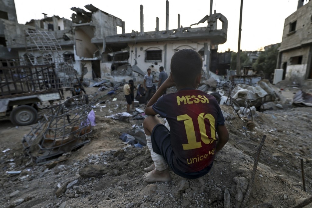 A Palestinian boy sits near residential buildings destroyed during recent Israeli strikes, on 1 June, in Beit Hanun 