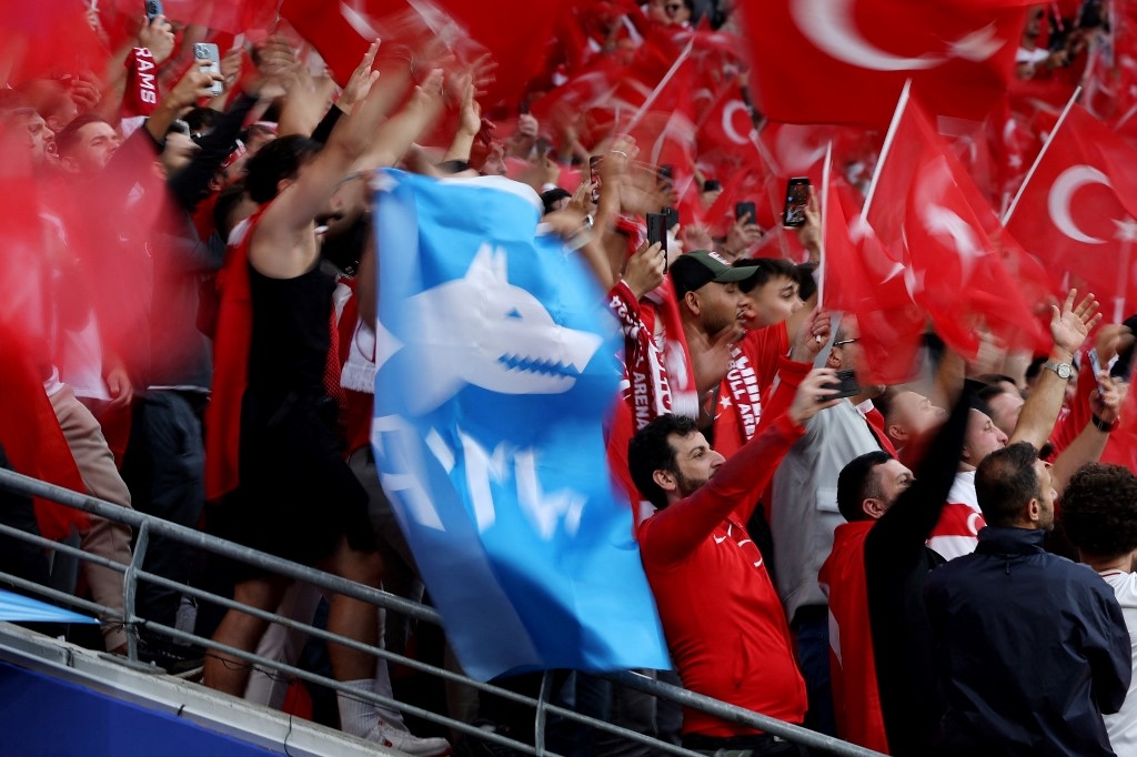 A participant standing among Turkey supporters waves the flag of Turkish ultra-nationalist group Grey Wolves prior to the UEFA Euro 2024 round of 16 football match between Austria and Turkey at the Leipzig Stadium in Leipzig, eastern Germany on July 2, 2024.  (Ronny Hartmann/AFP)