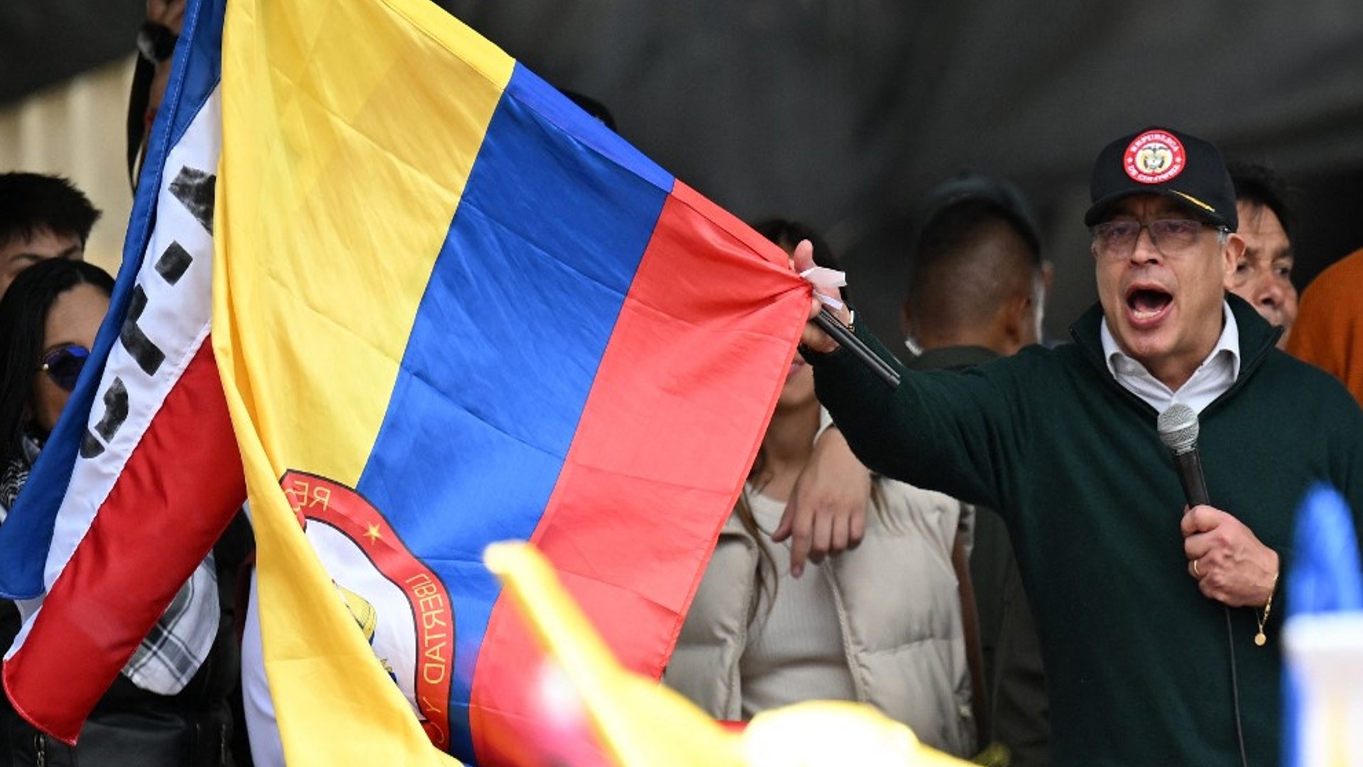 Colombian President Gustavo Petro waves a national flag as he delivers a speech during a May Day rally in Bogota on 1 May (Raul Arboleda/AFP)