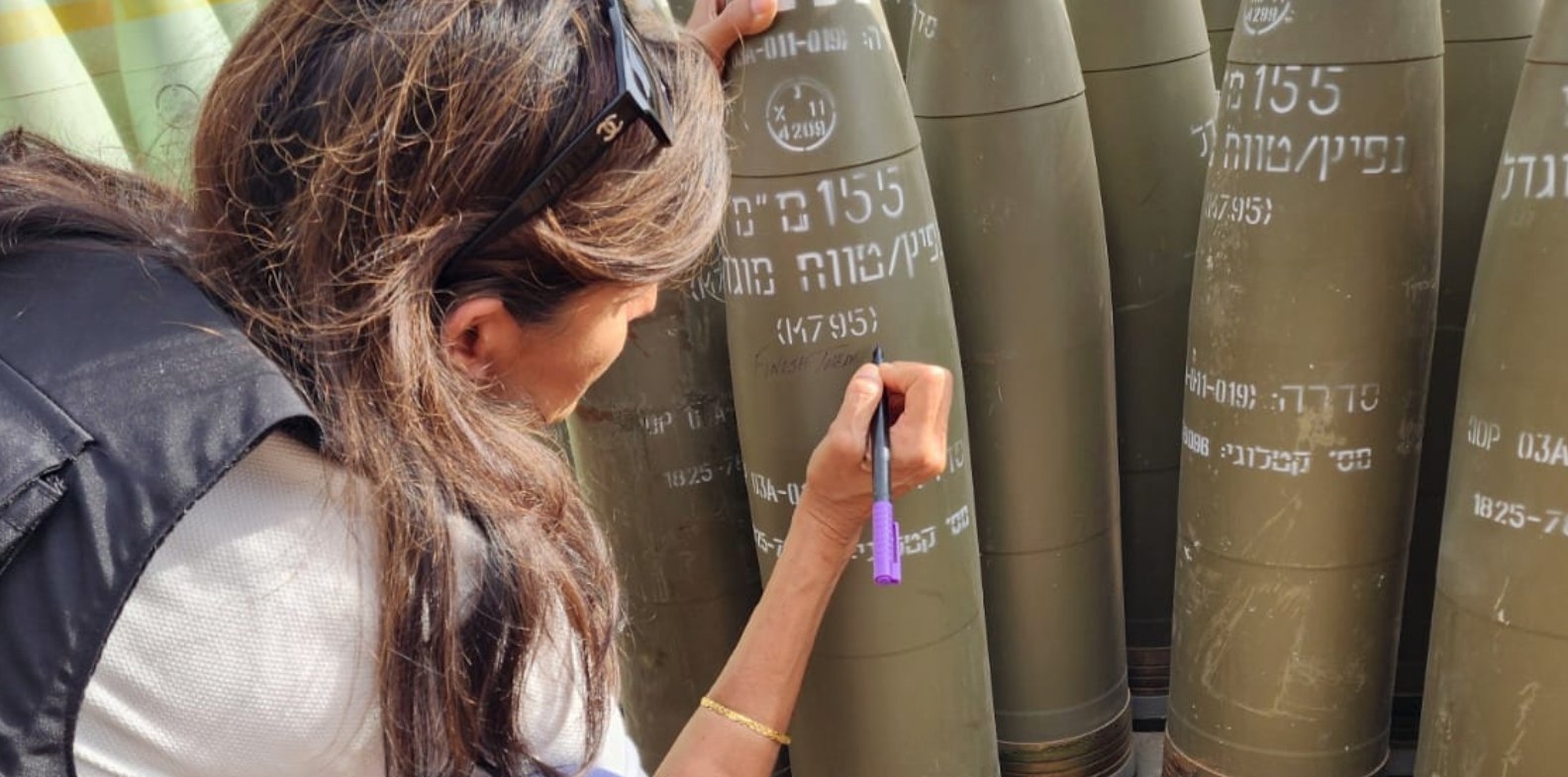 A picture posted on social media shows Nikki Haley writing 'finish them' on an Israeli shell (Danny Danon)