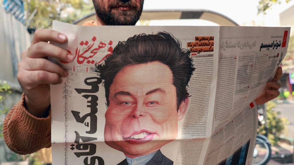 A man holds a copy of Iran's Farhikhtegan newspaper with a cartoon of Elon Musk on its front page, Tehran, 16 November 2024 (AFP)