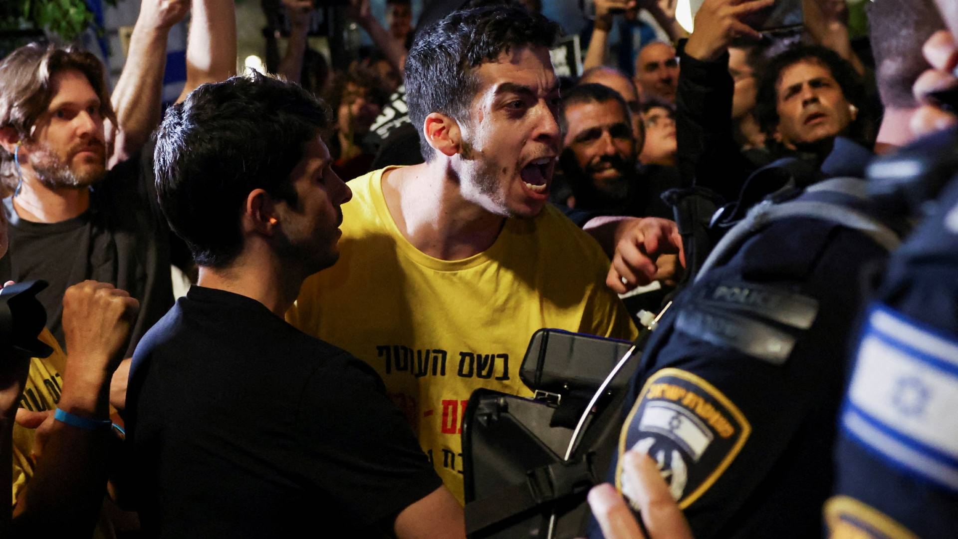 An angry Israeli demonstrator reacts in front of police officers during a protest against Israeli Prime Minister Benjamin Netanyahu's government, calling for the release of hostages on 18 May (Reuters)