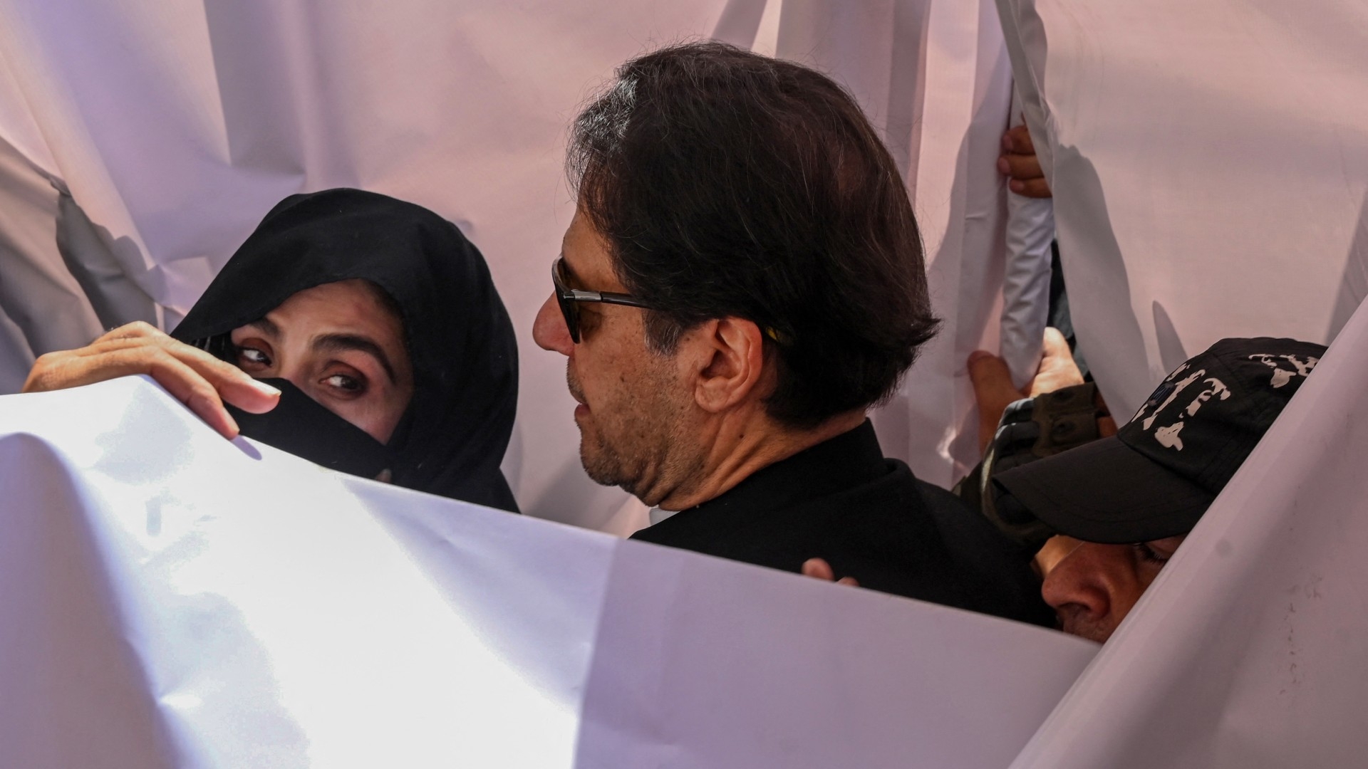 Former Pakistan Prime Minister Imran Khan with his wife Bushra Bibi arrive to appear at a high court in Lahore on 15 May 2023, before they were sentenced on 31 January 2024 to 14 years in jail (AFP)