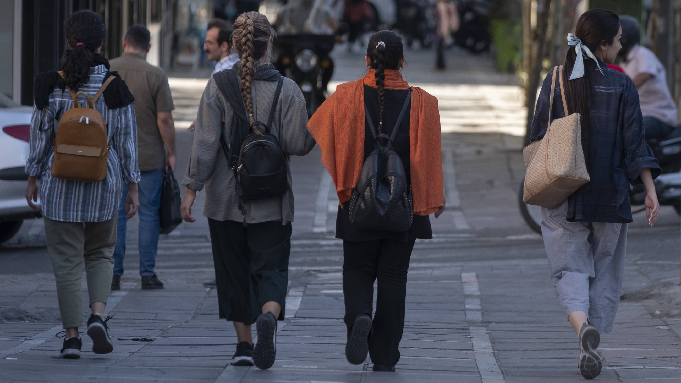Iranian women walk along an avenue in downtown Tehran without wearing mandatory headscarves, 12 September 2023 (AFP)