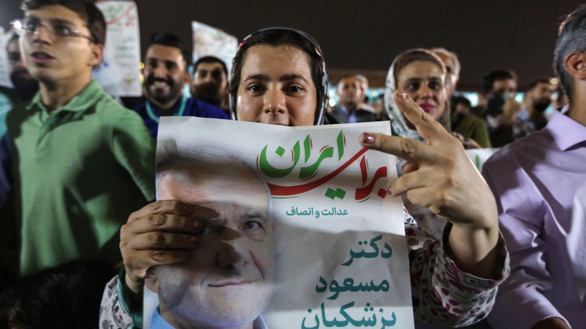 Supporters of reformist Iranian presidential candidate Massoud Pezeshkian lift his portraits during a rally in Tehran on 26 June 2024 (Raheb Homavandi/AFP)