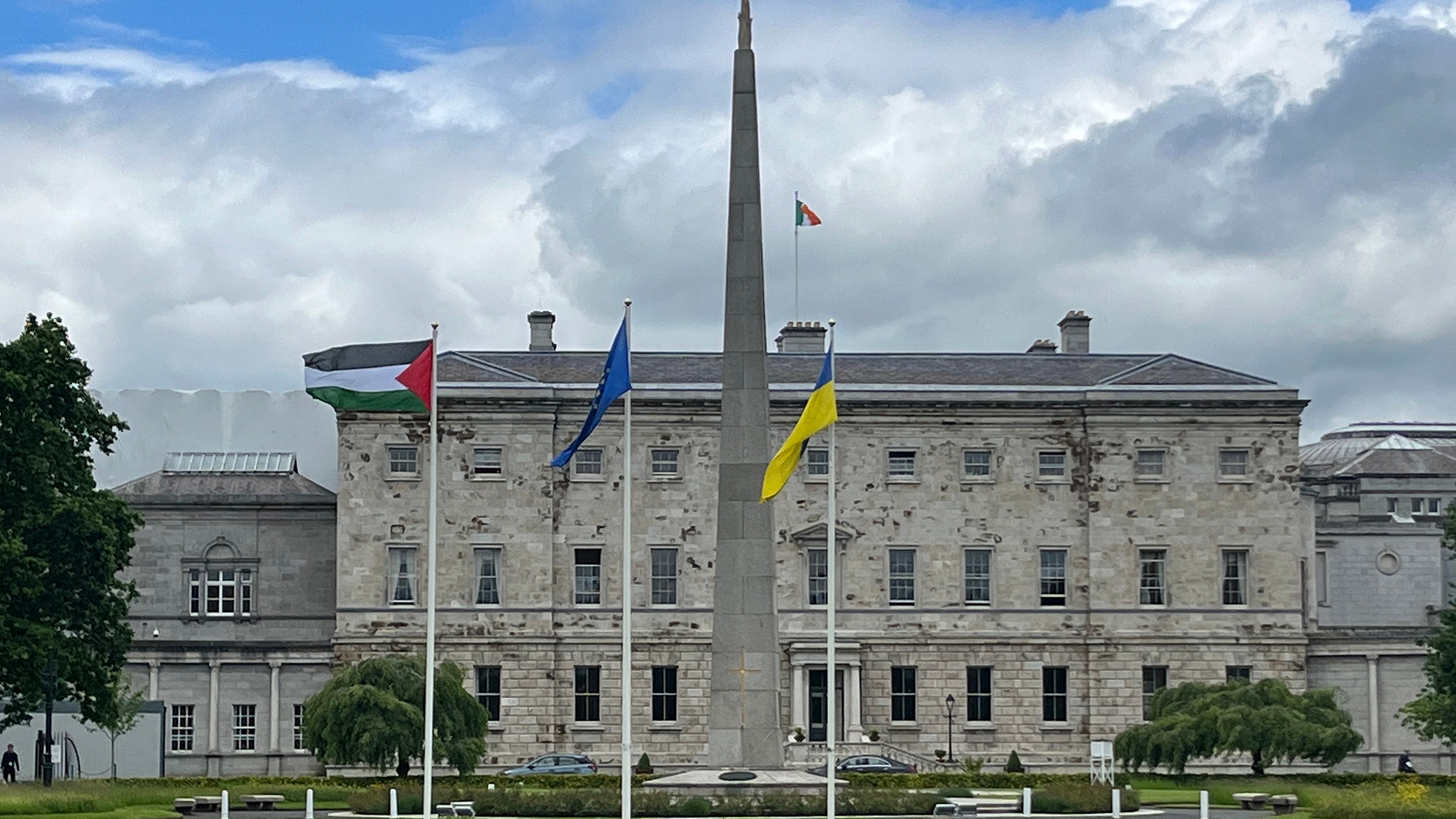A Palestinian flag, left, flutters alongside EU and Ukrainian flags outside Leinster House in Dublin on 28 May 2024 to mark Ireland's recognition of a Palestinian state (Peter Murphy/AFP)