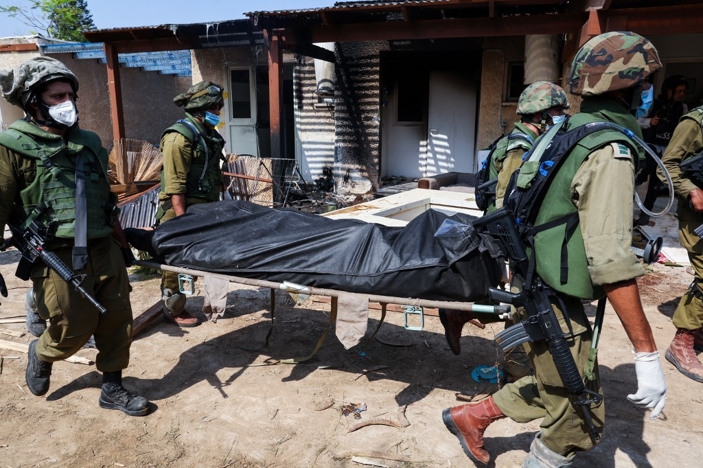 Israeli soldiers remove a body from a house in Kfar Aza on 10 October 2023 (AFP)
